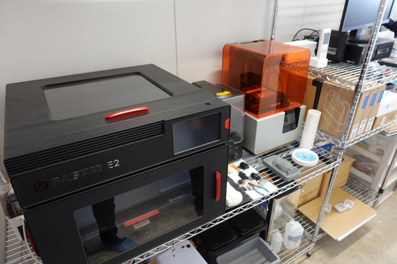 FDM方式（手前黒）と光造形方式（奥オレンジ）の3Dプリンター